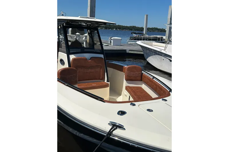 Slide: The Image of 2025 Scout 277 LXF boat with brown seating, docked by the water. - 37