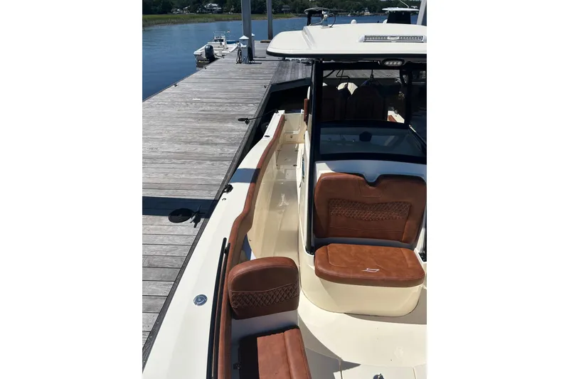 Slide: The Image of 2025 Scout 277 LXF boat docked, featuring luxurious brown leather seating. - 41