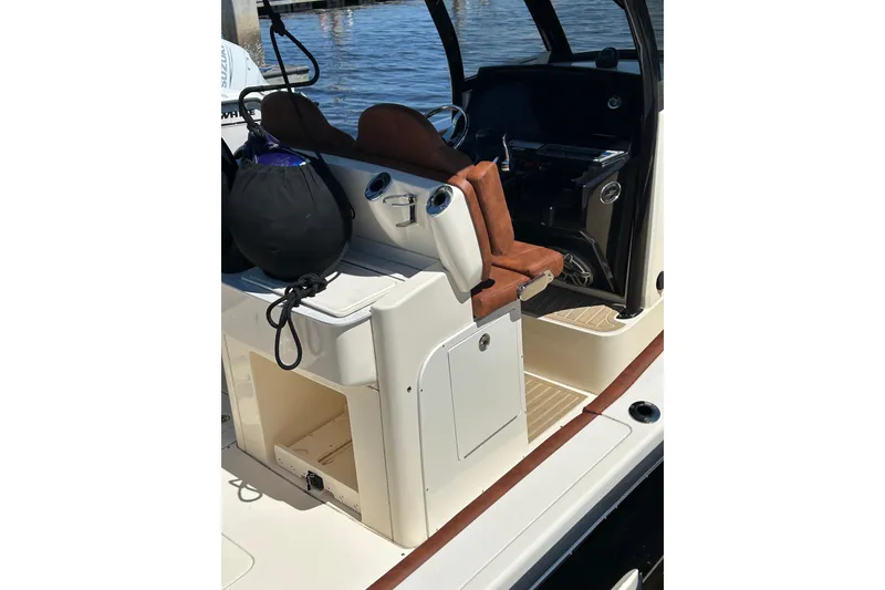 Slide: The Image of 2025 Scout 277 LXF boat interior with seating and storage, docked by the water. - 46