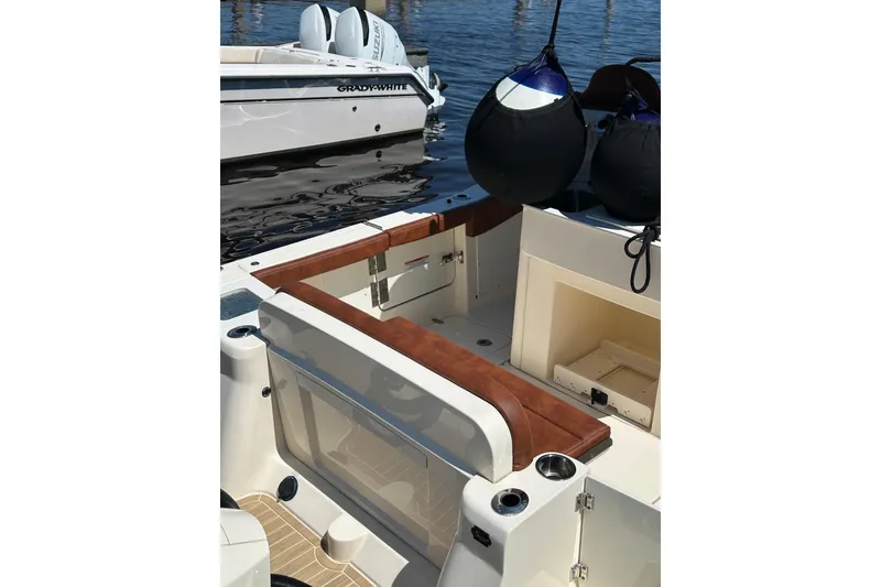 Slide: The Image of 2025 Scout 277 LXF boat interior with seating and storage, docked beside another vessel. - 49