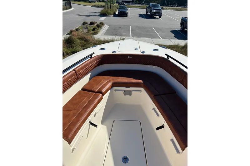 Slide: The Image of 2025 Scout 277 LXF boat with luxurious brown seating in a parking lot. - 52