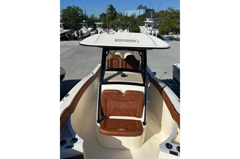 Slide: The Image of 2025 Scout 277 LXF boat with sleek design and luxurious seating in a marina setting. - 54