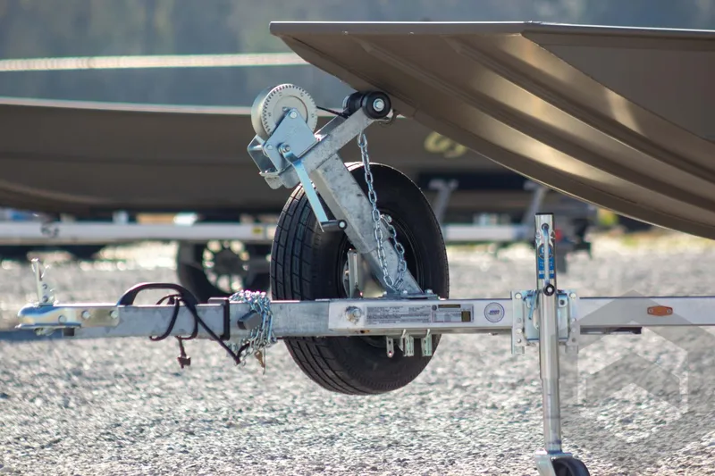 Slide: The Image of Trailer hitch and wheel of 2026 G3 Gator Tough 1652 VBW boat on gravel. - 5