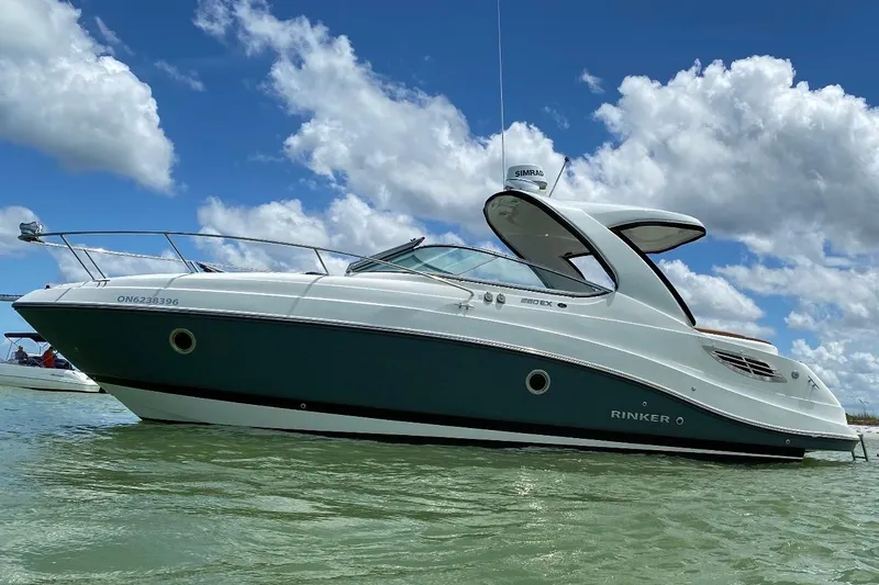The Image of 2019 Rinker EX 290 boat on water under a blue sky with clouds. - 0