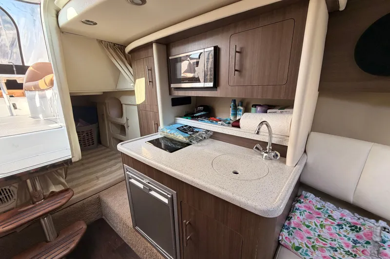 Slide: The Image of 2019 Rinker EX 290 boat interior with kitchenette, sink, and microwave. - 10