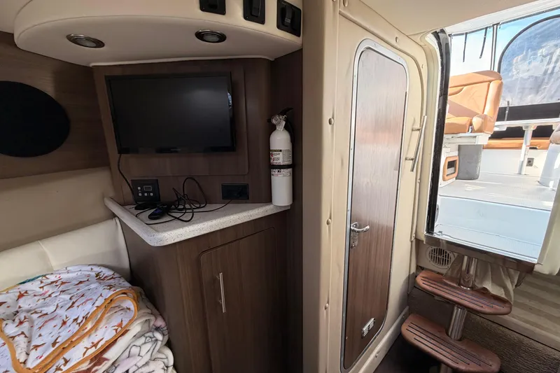 Slide: The Image of 2019 Rinker EX 290 cabin interior with TV, fire extinguisher, and cozy seating. - 11