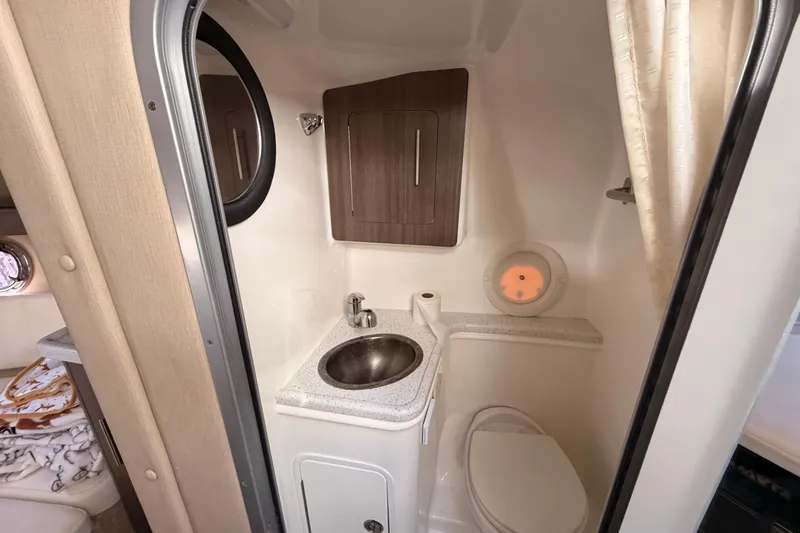 Slide: The Image of 2019 Rinker EX 290 boat bathroom with sink, toilet, and storage cabinet. - 12