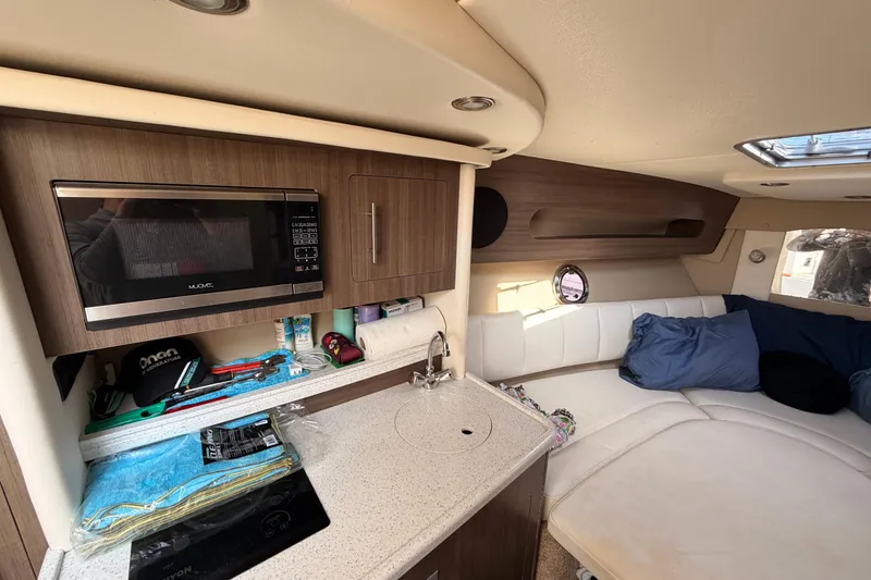 Slide: The Image of 2019 Rinker EX 290 cabin interior with kitchenette, microwave, and seating area. - 15