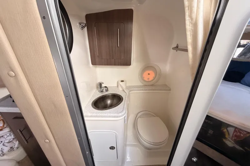 Slide: The Image of 2019 Rinker EX 290 boat bathroom with sink, toilet, and storage cabinet. - 18