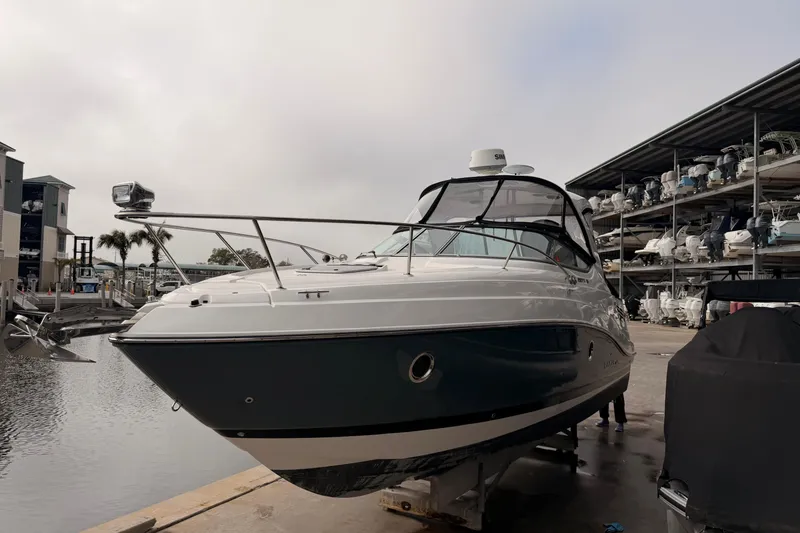 Slide: The Image of 2019 Rinker EX 290 boat docked at marina with covered storage in background. - 2