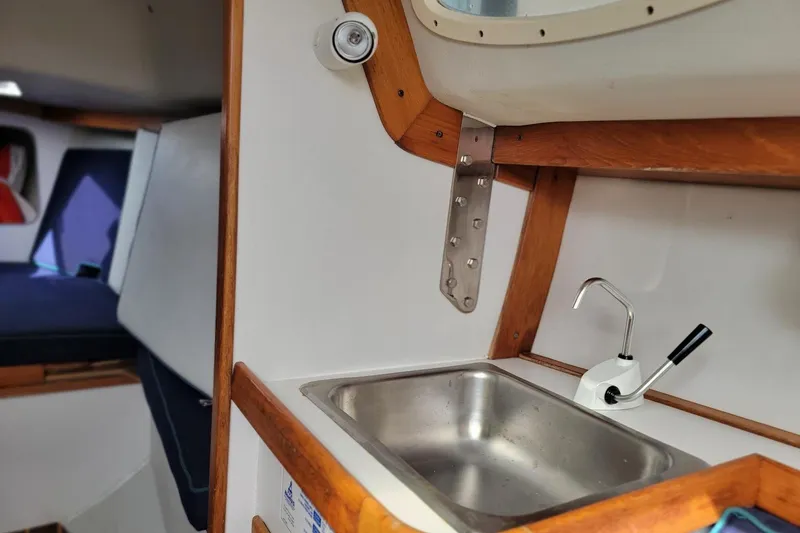 Slide: The Image of Interior of 2002 Alerion 28 Express sailboat, featuring a compact sink and cozy cabin space. - 12