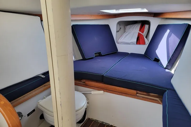 Slide: The Image of Interior cabin of 2002 Alerion 28 Express sailboat with blue cushions and compact toilet. - 4
