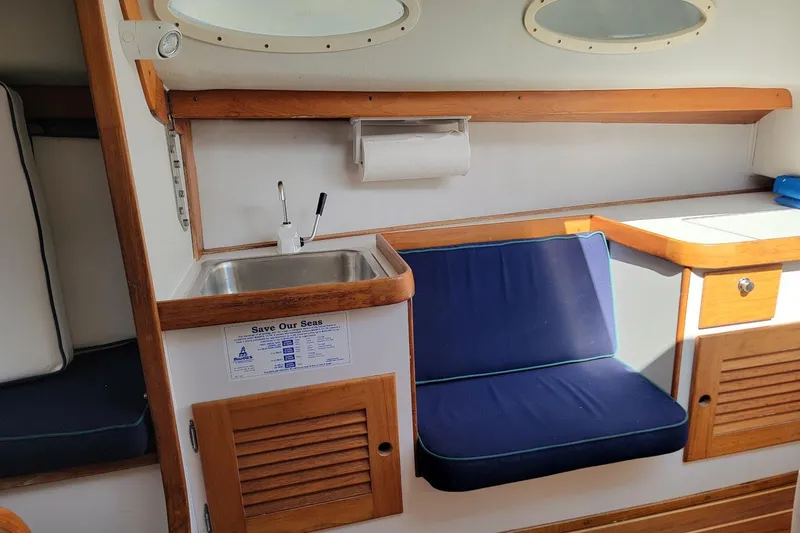 Slide: The Image of Interior of 2002 Alerion 28 Express sailboat with sink, seating, and wooden cabinetry. - 8