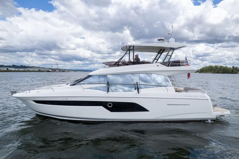 The Image of 2022 Prestige 520 yacht cruising on a calm lake under a cloudy sky. - 0