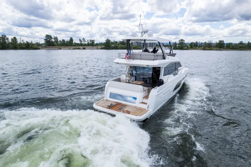 Slide: The Image of 2022 Prestige 520 yacht cruising on a scenic lake under a cloudy sky. - 2