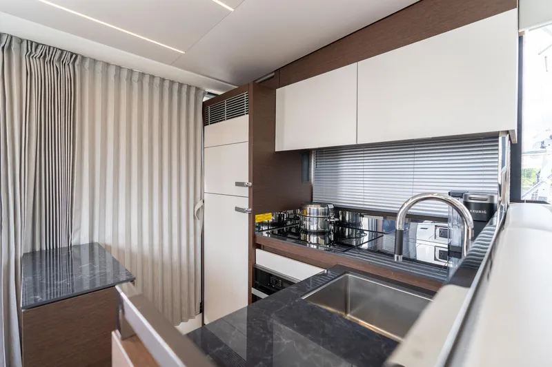 Slide: The Image of Modern kitchen interior on a 2022 Prestige 520 yacht, featuring sleek cabinetry and appliances. - 24