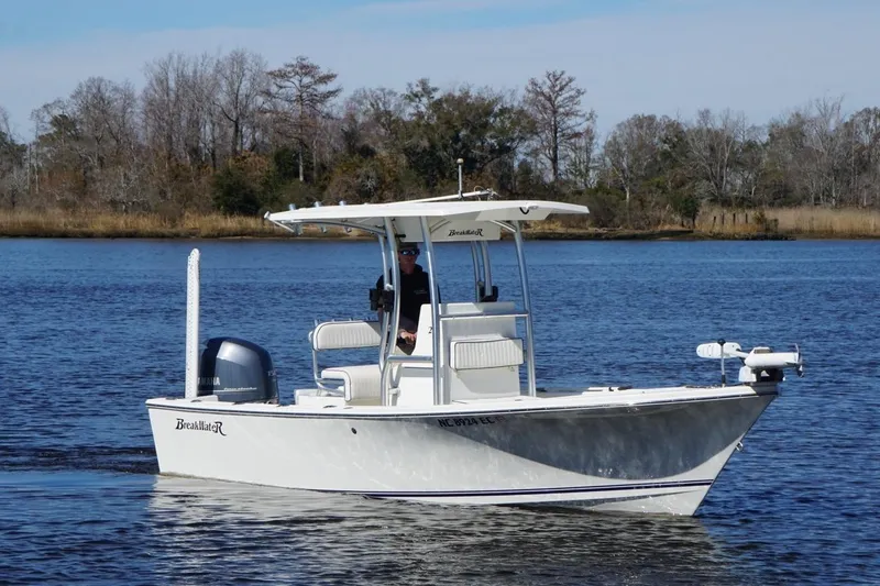 Slide: The Image of 2015 KenCraft BreakWater 20 boat cruising on a calm lake with trees in the background. - 2