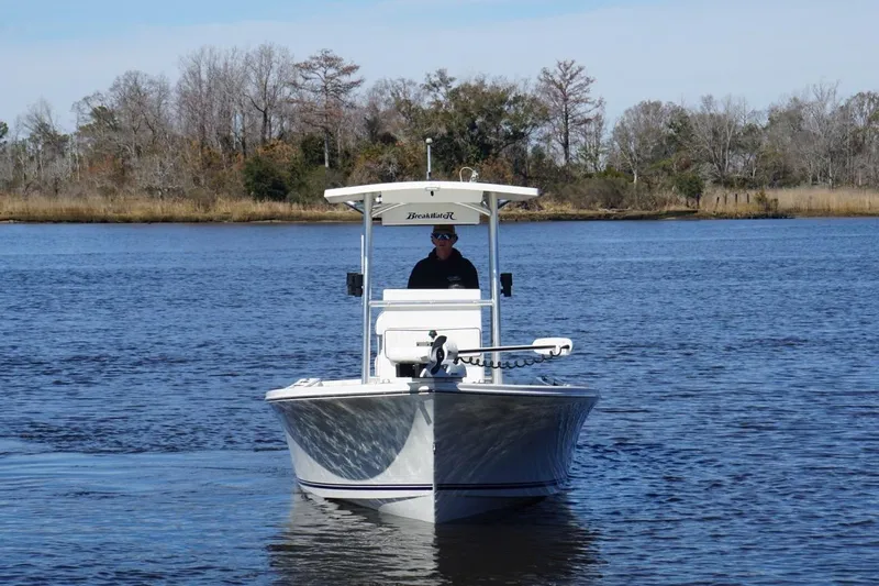 Slide: The Image of 2015 KenCraft BreakWater 20 boat cruising on a calm lake with trees in the background. - 4