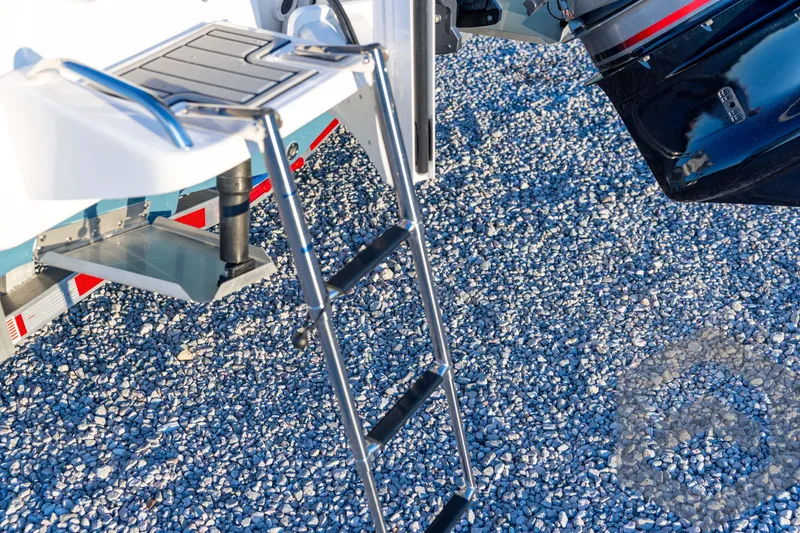 Slide: The Image of 2026 Tidewater 2110 Bay Max boat ladder and motor on gravel surface. - 23