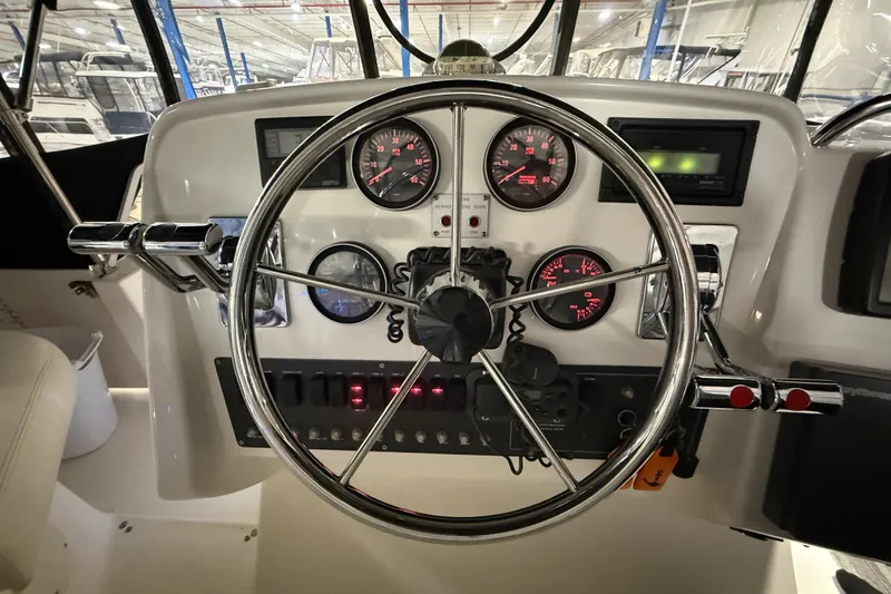 Slide: The Image of 1998 Silverton 352 Motor Yacht helm with gauges and steering wheel in a marina setting. - 19