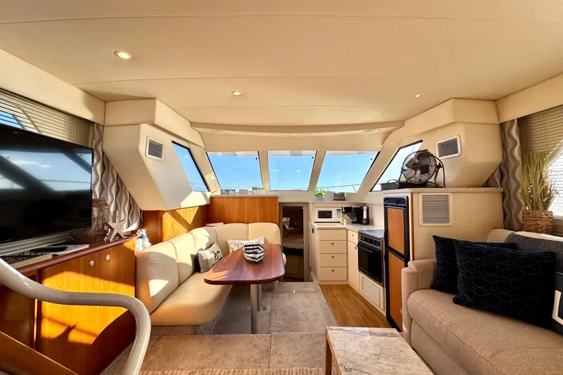 Slide: The Image of Interior of a 1998 Silverton 352 Motor Yacht, featuring a cozy living area and kitchenette. - 25