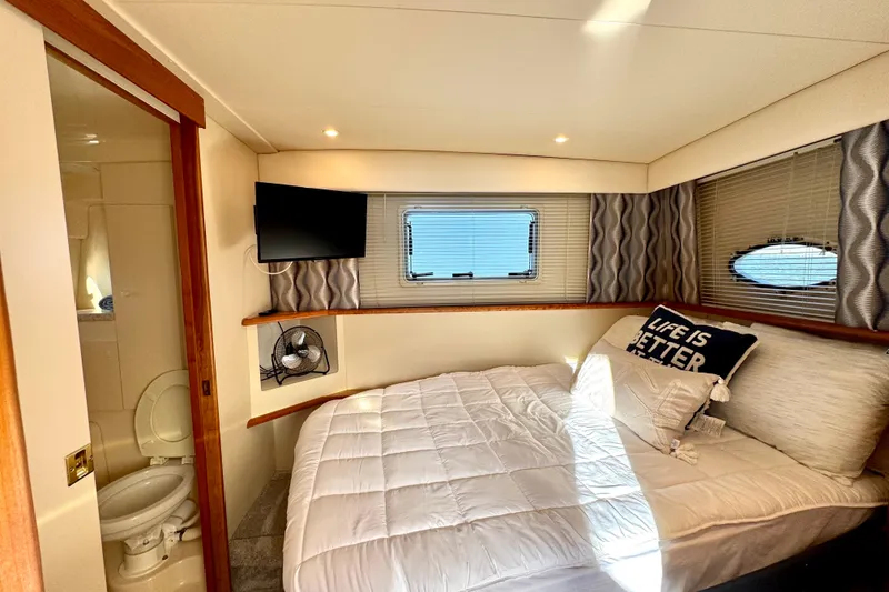 Slide: The Image of 1998 Silverton 352 Motor Yacht bedroom with ensuite bathroom, cozy bed, and TV. - 36