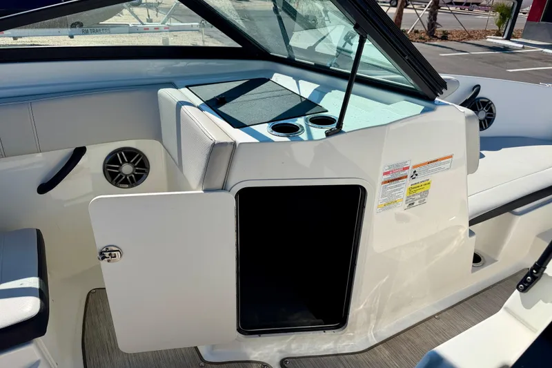 Slide: The Image of 2023 Sea Ray SPX 210 Outboard interior with open storage compartment and cup holders. - 26