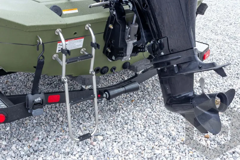 Slide: The Image of 2026 Vexus Defender 181 boat rear view with motor and ladder on gravel. - 28