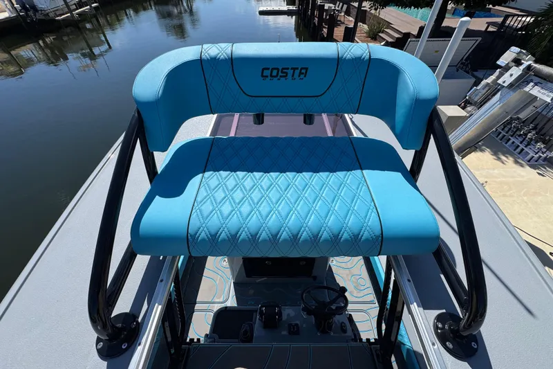 Slide: The Image of 2026 Costa Custom Boats 264 HC with blue seating, docked by the water. - 14