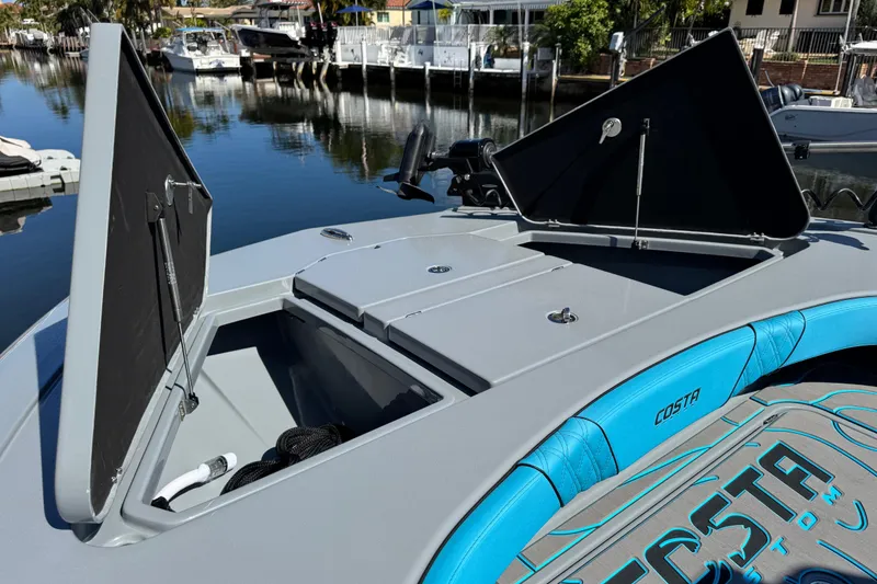 Slide: The Image of 2026 Costa Custom Boats 264 HC with open storage compartments, docked by a serene waterfront. - 43