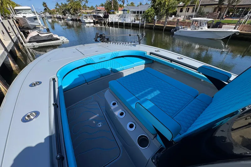 Slide: The Image of 2026 Costa Custom Boats 264 HC with blue seating, docked in a scenic marina. - 6