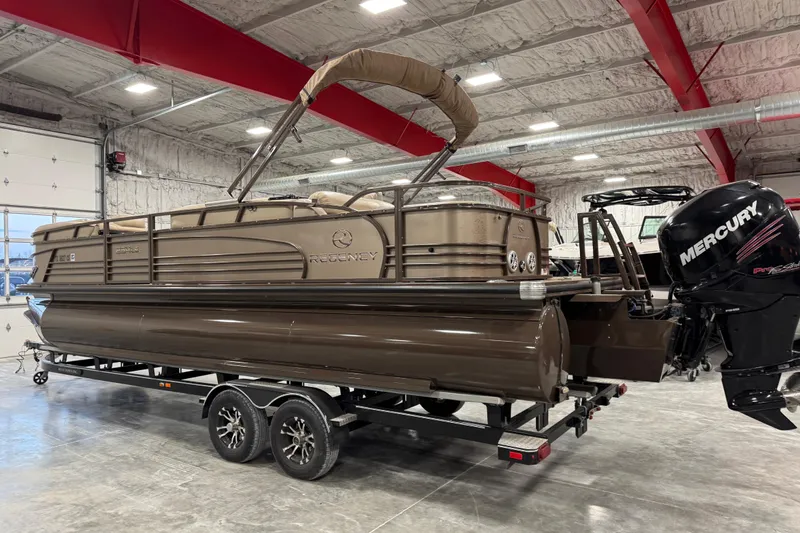 Slide: The Image of 2015 Sun Tracker Regency 254 XP3 pontoon boat in a warehouse, featuring a Mercury outboard motor. - 4