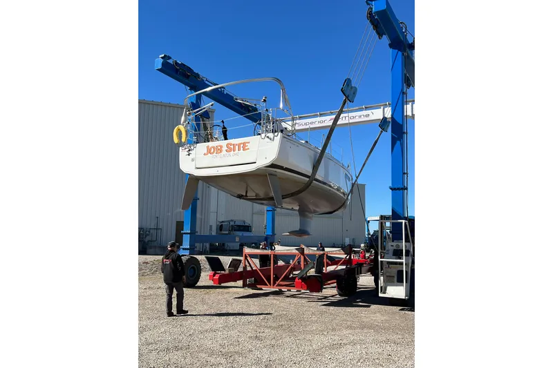 Slide: The Image of 2023 Jeanneau Sun Odyssey 380 sailboat being lifted by a crane at a marina. - 9