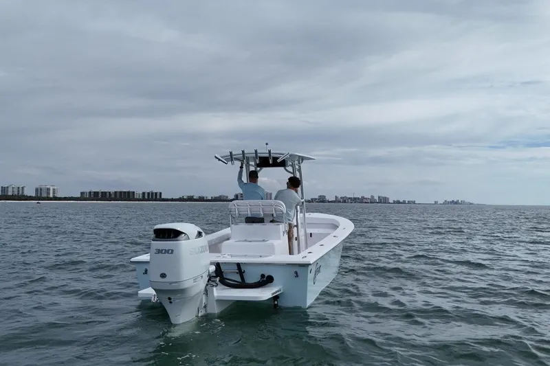 Slide: The Image of 2026 C-Hawk 25 Center Console boat cruising on open water near city skyline. - 2