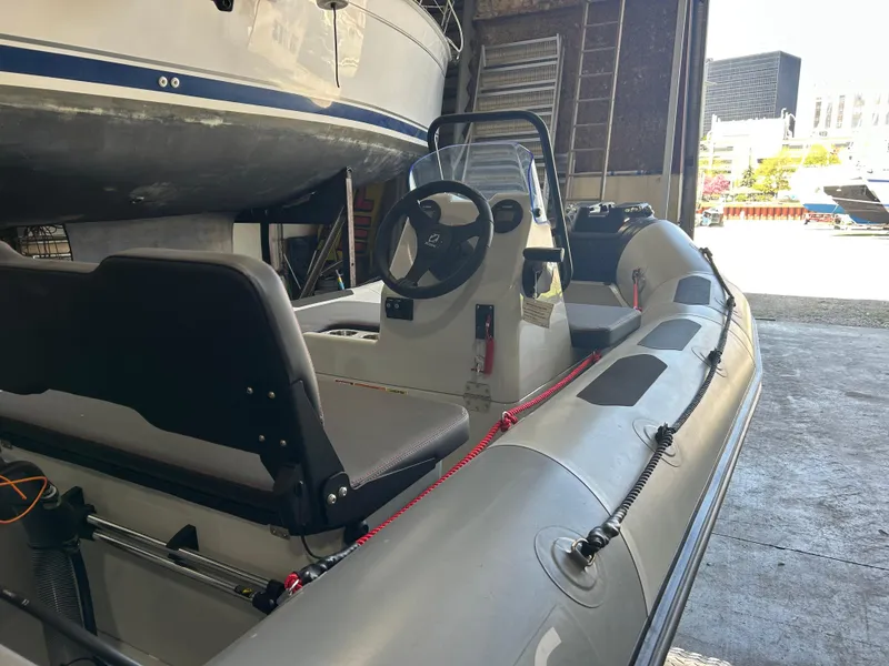 The Image of 2025 Zodiac Open 4.2 inflatable boat in a storage facility, showcasing steering console and seating. - 0