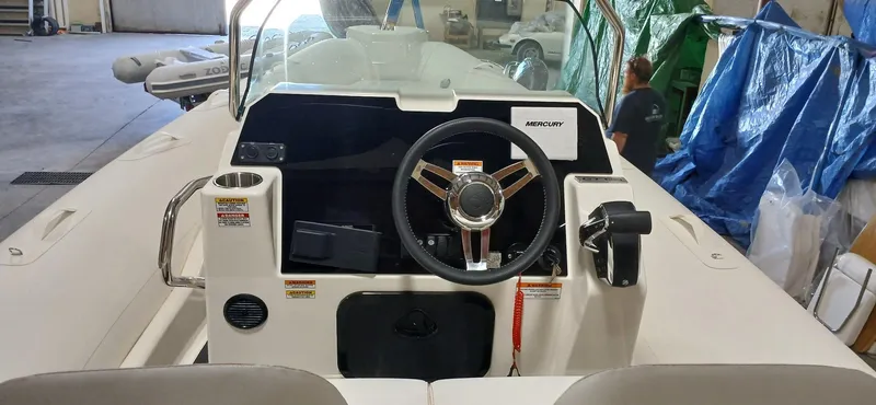 Slide: The Image of 2025 Zodiac Medline 7.5 GT boat interior with steering wheel and Mercury controls. - 7