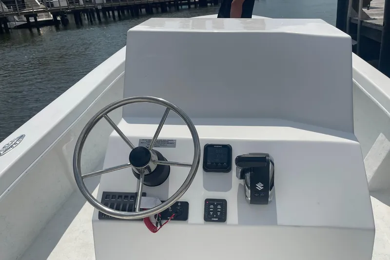 Slide: The Image of 2026 C-Hawk 26 Center Console boat steering wheel and controls by the water. - 6
