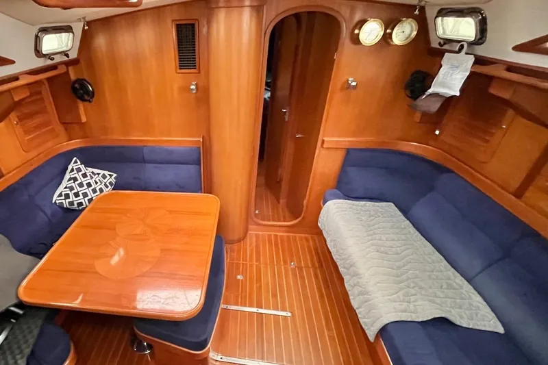 Slide: The Image of 2004 Hylas 49 yacht interior with wooden finish, blue seating, and dining area. - 9