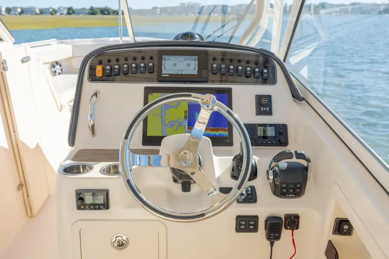 Slide: The Image of Grady-White Freedom 307 2020 boat dashboard with steering wheel and navigation controls. - 23
