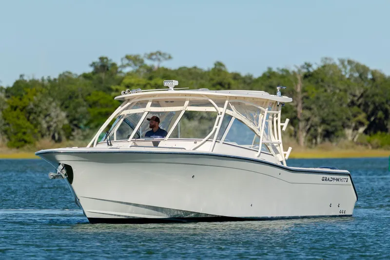 Slide: The Image of 2020 Grady-White Freedom 307 boat cruising on a serene lake with lush greenery. - 4