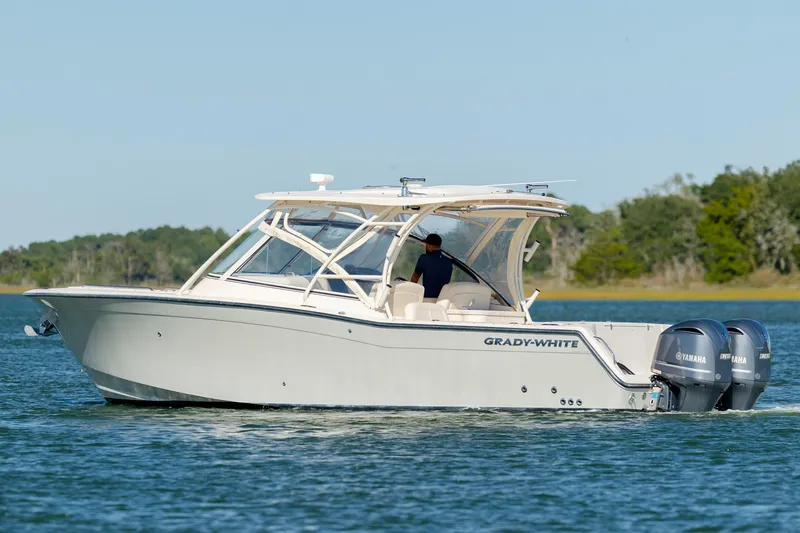 Slide: The Image of 2020 Grady-White Freedom 307 boat cruising on a serene lake with dual Yamaha engines. - 6