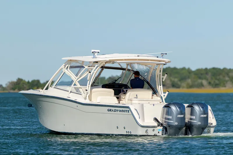 Slide: The Image of 2020 Grady-White Freedom 307 boat cruising on a calm lake with dual Yamaha engines. - 7