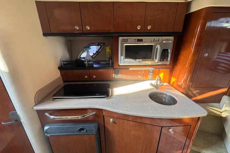 Slide: The Image of 2007 Sea Ray Sundancer 310 galley with microwave, sink, and wooden cabinetry. - 12
