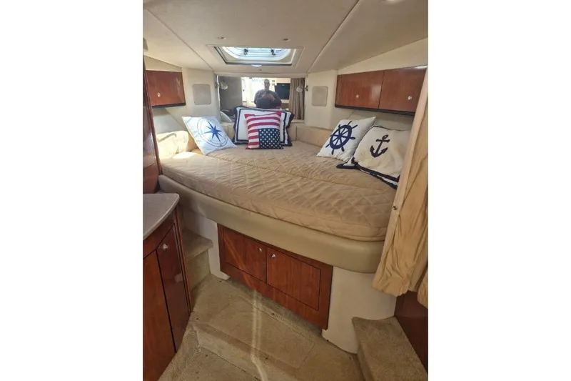 Slide: The Image of 2007 Sea Ray Sundancer 310 cabin interior with nautical-themed pillows and cozy bedding. - 27