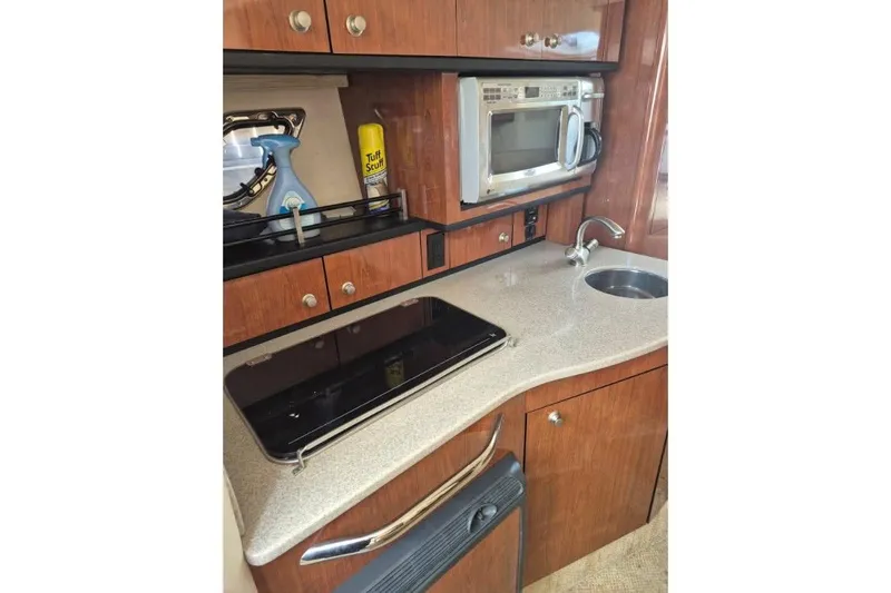 Slide: The Image of 2007 Sea Ray Sundancer 310 galley with microwave, sink, and storage cabinets. - 34