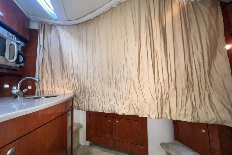 Slide: The Image of 2007 Sea Ray Sundancer 310 interior with kitchenette, sink, and beige curtains. - 58