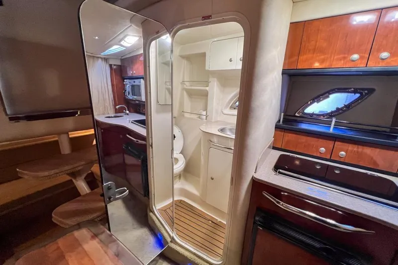 Slide: The Image of Interior of 2007 Sea Ray Sundancer 310, featuring kitchenette and bathroom with wood accents. - 62