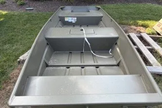 The Image of 2026 Tracker Grizzly 15 Jon boat on grass, showcasing interior seating and storage. - 0