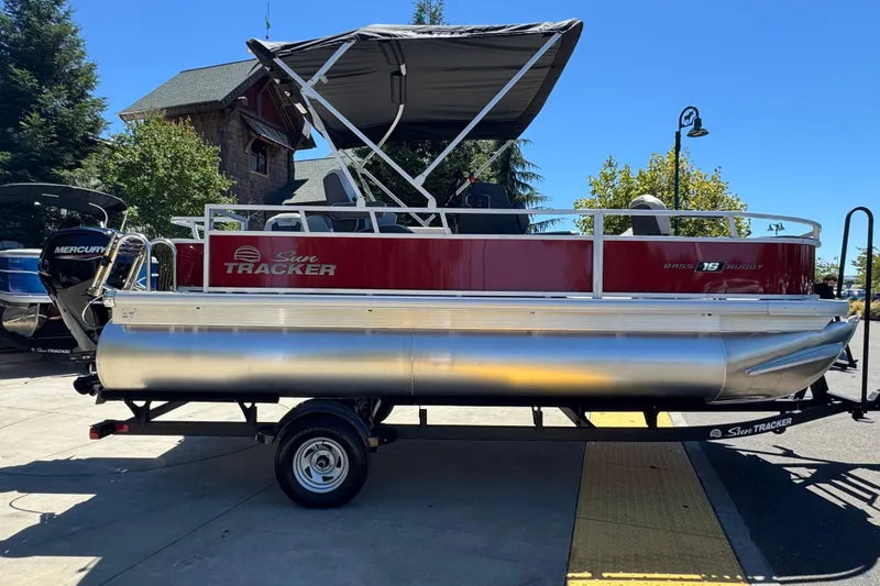 Slide: The Image of 2026 Sun Tracker Bass Buggy 18 DLX pontoon boat on trailer, parked outdoors. - 4