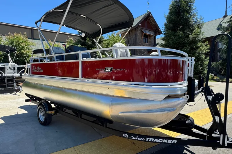 Slide: The Image of 2026 Sun Tracker Bass Buggy 18 DLX pontoon boat on trailer, parked outdoors. - 5